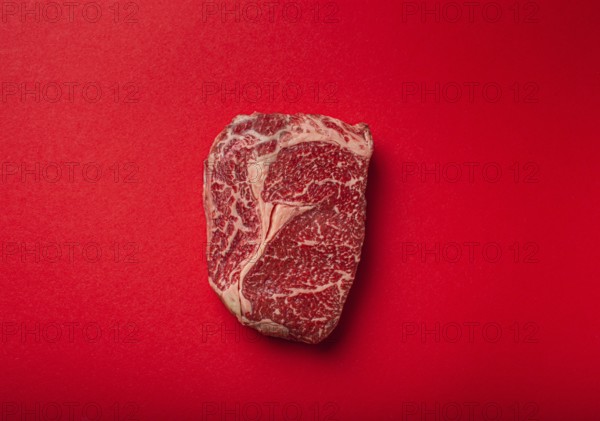 Raw fresh uncooked meat beef prime cut steak Ribeye on clean red background from above, beefsteak concept banner minimalism