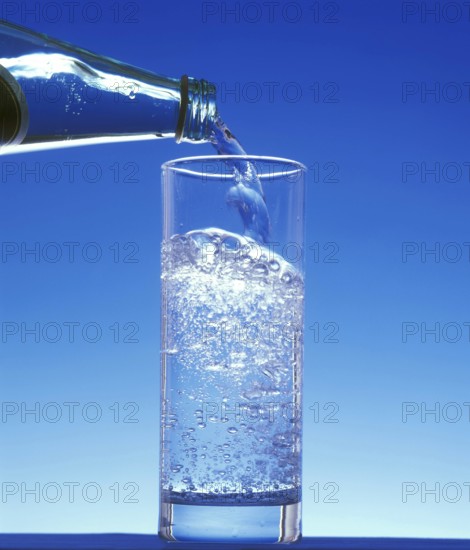 Sparkling Water being Poured in a Glass against Blue Background