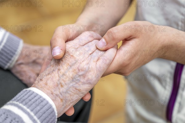 Close-up senior woman hand with her caregiver helping hands holding together, Caregiver visit at home. Home health care and nursing home concept. High quality photo