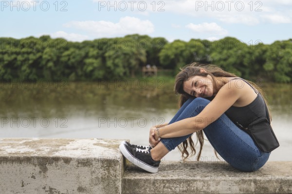 Young woman sitting on the waterfront looking at the camera
