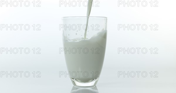 Milk being poured into Glass against White Background