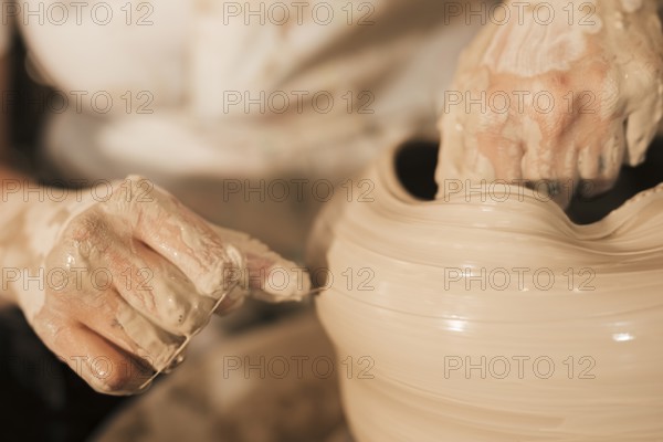Potter aligns wet clay pot with thread potter s wheel