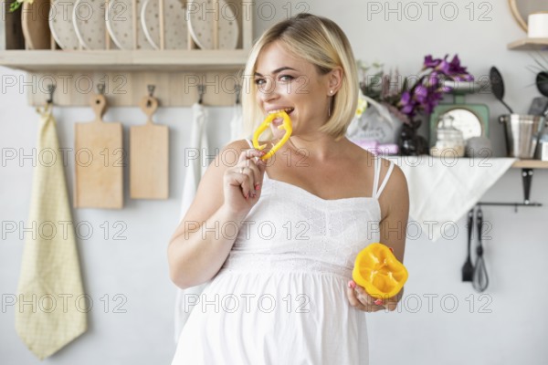 Beautiful pregnant woman eating yellow pepper