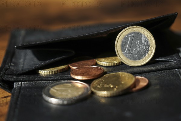 black leather wallet with euro and cent coins close-up