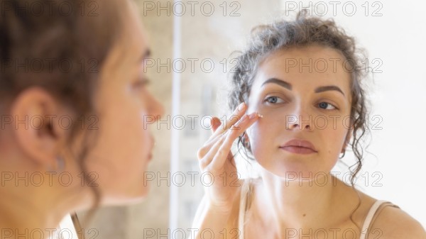 Woman looking mirror applying cream face
