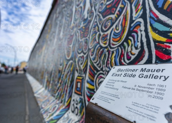 Berlin, Germany - 25 August 2020: view of a mural on the Berlin Wall at the famous East Side Gallery with information plaque
