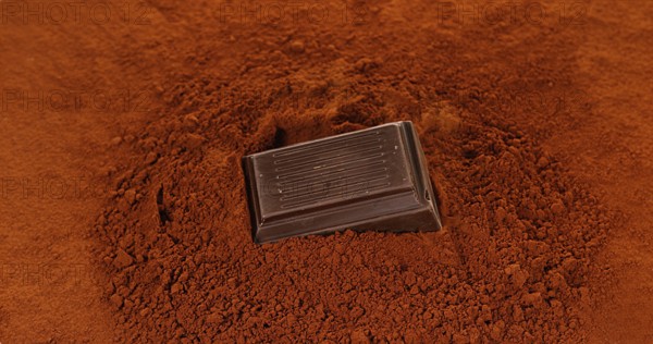 Black Chocolate Tablet falling on Black Chocolate Powder