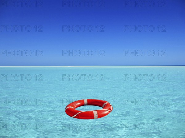 Red lifebuoy floating on turquoise blue water in the sea, ocean, location unknown