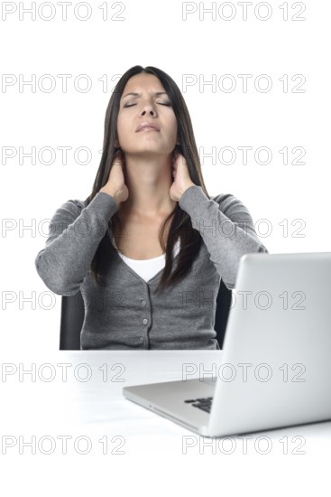 Attractive young businesswoman sitting at her laptop rubbing her neck with a grimace to relieve stiffness after sitting at the computer for too long