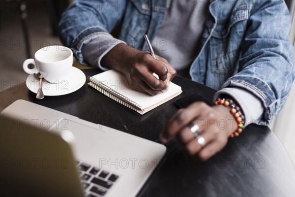 Unrecognisable man writing notebook