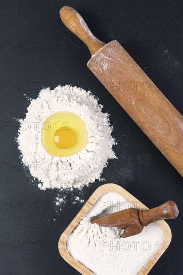 Rolling pin and white flour on a dark background. Top view
