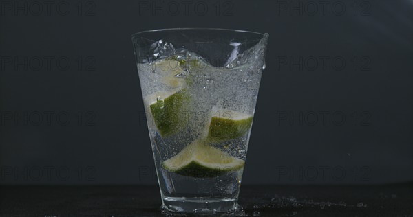 Green Citrus (citrus aurantifolia), falling into a Glass of Water
