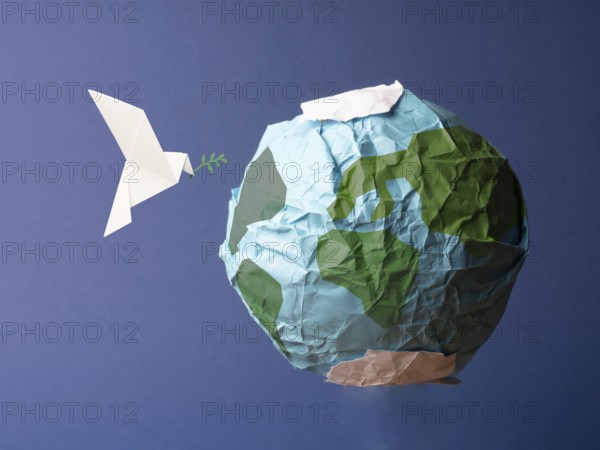 Abstract globe made of crumpled paper with origami peace dove, global freedom and peace concept