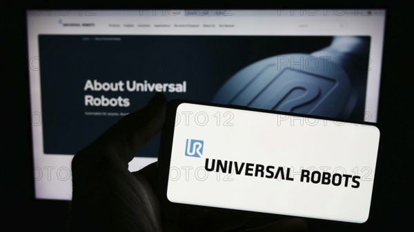 Stuttgart, Germany, 02-12-2024: Person holding smartphone with logo of Danish cobot company Universal Robots AS in front of website. Focus on phone display, Europe