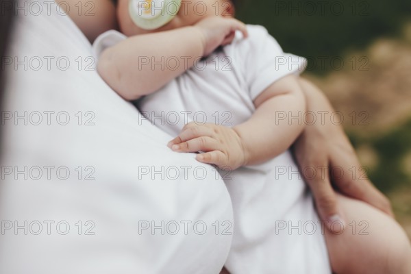 Little baby's hands, mother with baby, care of baby, mother carrying baby.