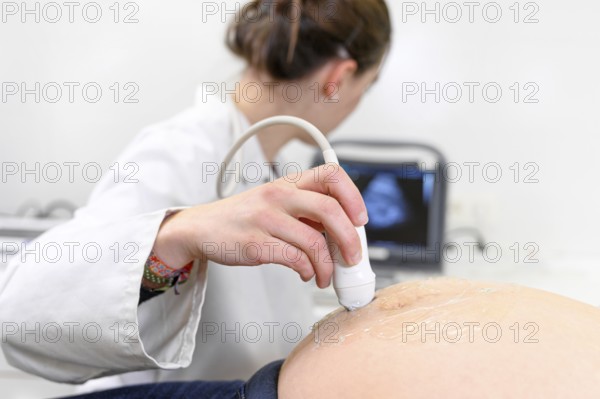 Doctor does Ultrasound or Sonogram Procedure to a Pregnant Woman in the Hospital, Close-up Shot of the Obstetrician Moving Transducer on the Belly of the Future Mother