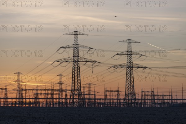 Rows of high-voltage pylons stretch into the twilight, Wolmirstedt substation, Saxony-Anhalt, Germany, Europe