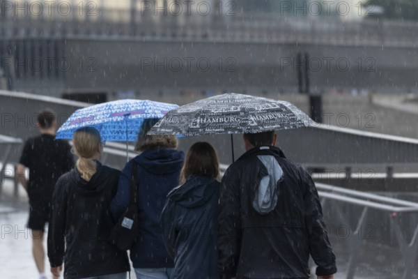 Symbolic picture weather, heavy rain in summer, thunderstorm, thunderstorm, tourists with umbrellas on the way in the rain at the jetties in the harbour of Hamburg, Germany, Europe