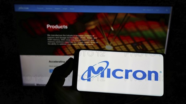 Stuttgart, Germany, 12-01-2022: Person holding smartphone with logo of US semiconductor company Micron Technology Inc. on screen in front of website. Focus on phone display, Europe