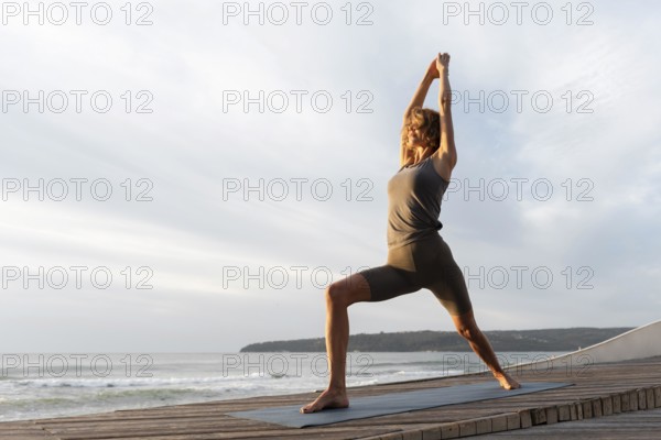 Full shot woman practicing yoga mat near sea