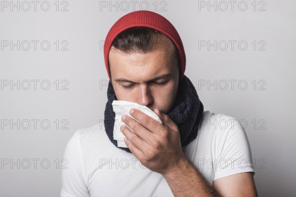 Young man suffering from cold flu against gray background