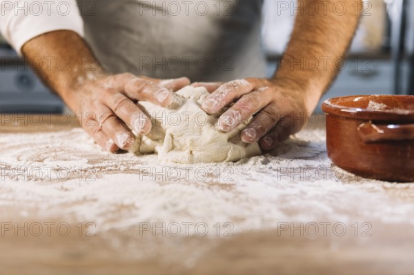 male baker kneading dough flour wooden table. Beautiful photo