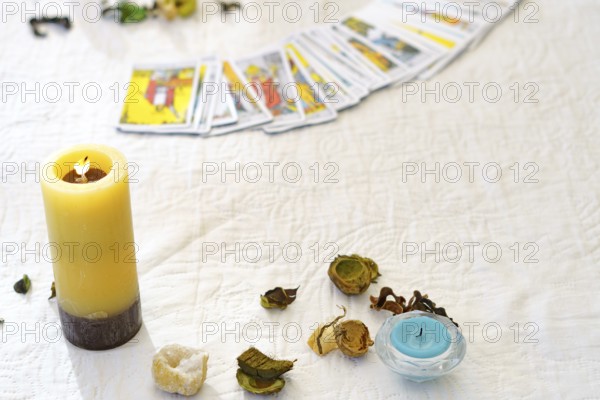Table of a fortune teller with tarot cards, candles, quartz stones, crystal ball on a white tablecloth