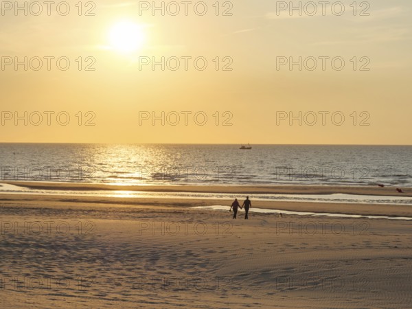 Couple walking along a quiet beach at sunset, oostende, belgium