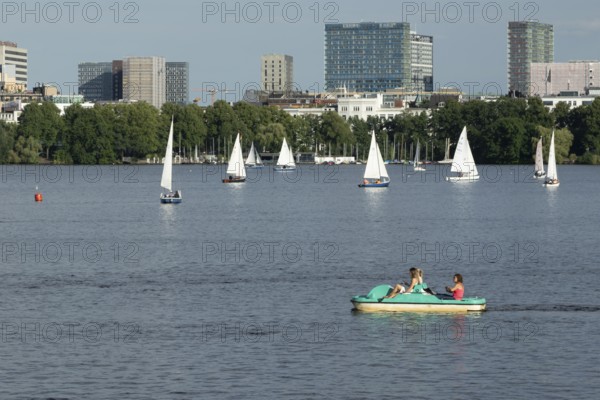 Symbolic picture weather, leisure activities in summer, people in a pedal boat, behind them sailing boats against a blue sky on the Alster in Hamburg, Germany, Europe