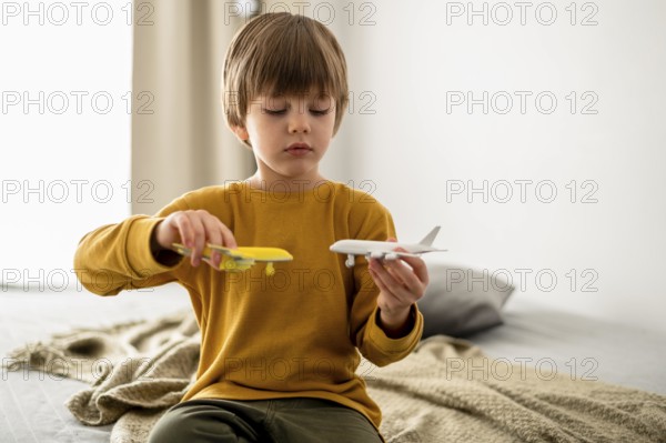 Front view kid playing with airplane figurines