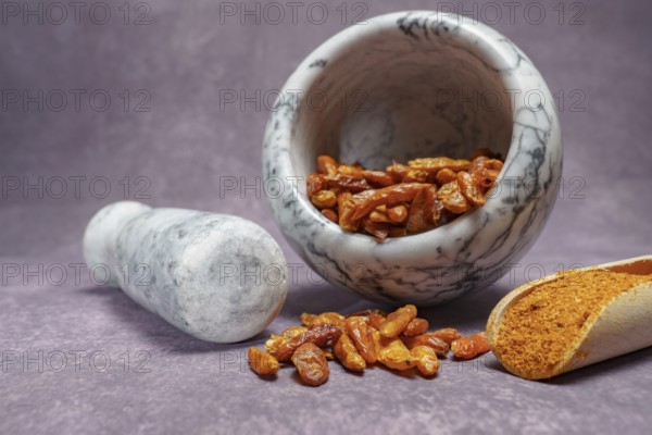 Whole cayenne pepper in a white marble mortar and ground cayenne pepper in a wooden spoon