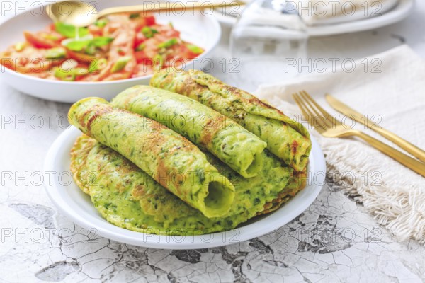 Delicious homemade ramson pancakes or crepes with tomato salad on white background
