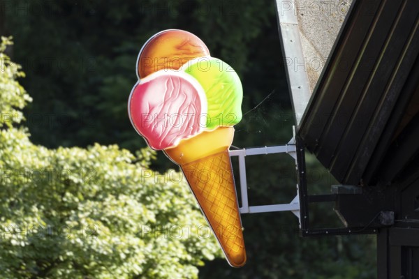 Illuminated sign in the shape of a colourful ice cream cone at an ice cream parlour in Planten un Blomen, Hamburg, Germany, Europe