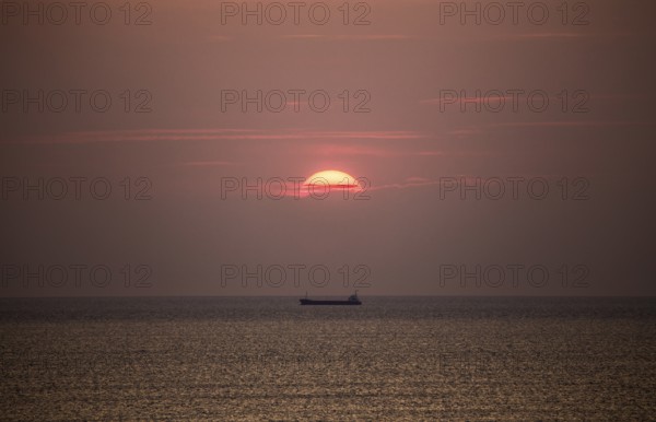 Cargo ship in the Mediterranean Sea under the evening sun, photographed from the beach near Tarragona, Catalonia, Spain, Europe