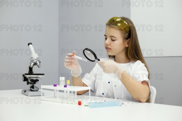Girl scientist with safety glasses microscope