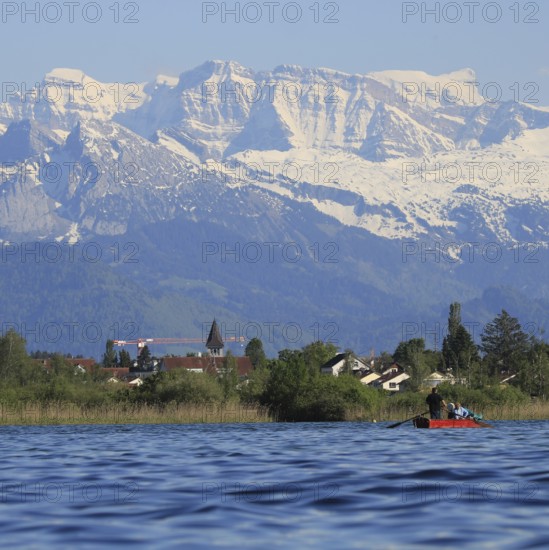 Blue water of Lake Pfaffikon, Pfaeffikon. Reed and church. Snow covered peaks