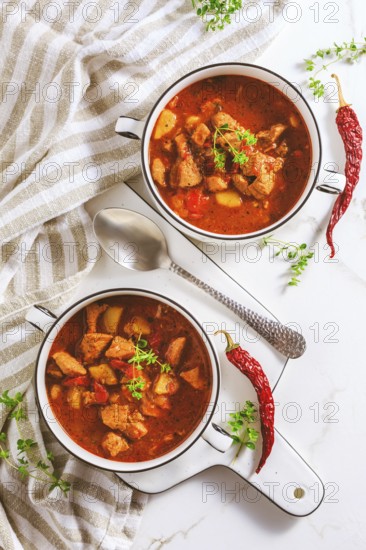 Beef goulash soup - hearty Hungarian soup of meat and vegetables seasoned with paprika on white background