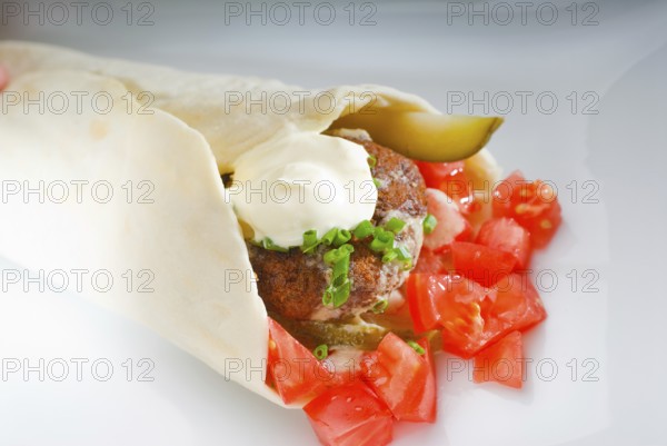 Fresh traditional falafel wrap on pita bread with fresh chopped tomatoes