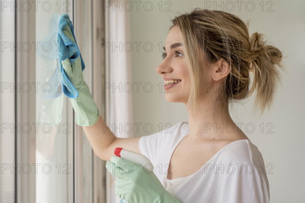 Side view smiley woman cleaning window