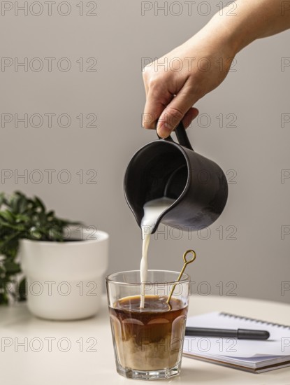 person pouring cream coffee glass