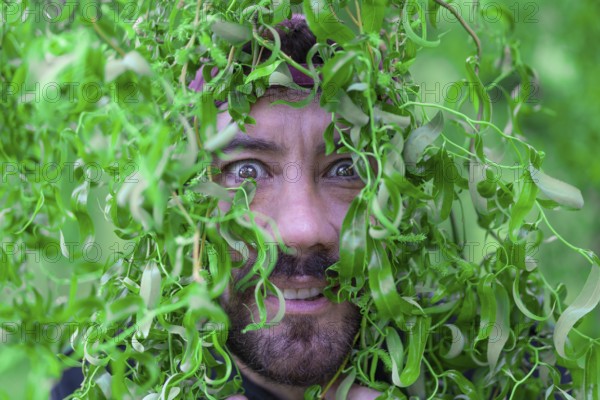 Close-up portrait of Latin man with funny expression among tree leaves