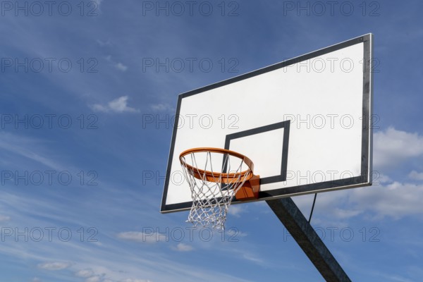 isolated view of a basketball hoop and backboard under an expressive blue sky with copy space