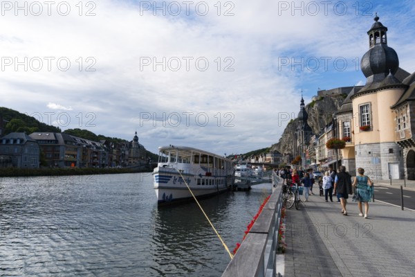 Belgium - 11 August 2019: horizontal view of tourists enjoying an evening walk along the Meuse river in the historic old town of Dinant in Belgium