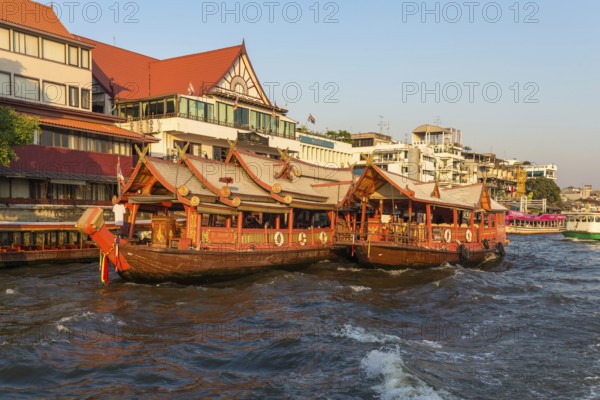 Ships at the pier for river cruise on a rice barge on the Chao Phraya river in Bangkok. Traditional rice barge, built for gastronomy on the river