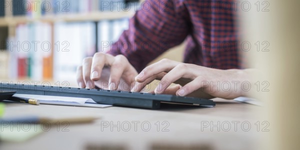 Typing hands on keyboard, home office with text space