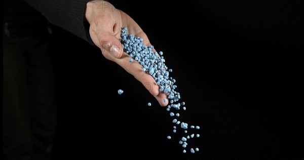 Hand of Woman with Soil Fertilizer against Black Background