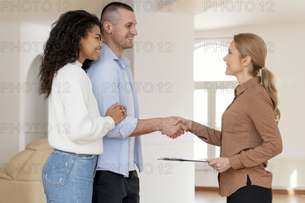 Side view female realtor shaking hands with couple new house deal