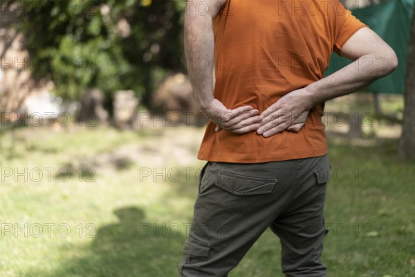 Latin man in a park massages his sore waist
