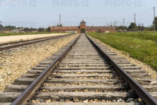 Auschwitz, Poland - 15 September, 2021: selective focus low angle view of the railroad tracks leading to the gatehouse at the Auschwitz concentration camp in Poland