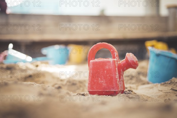 Children plastic toys in the sand box. Watering can, selective focus